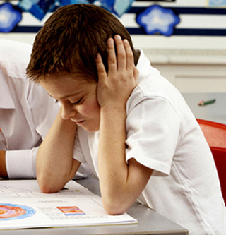 Group Of Primary Schoolchildren And Teacher Working At Desks In Classroom